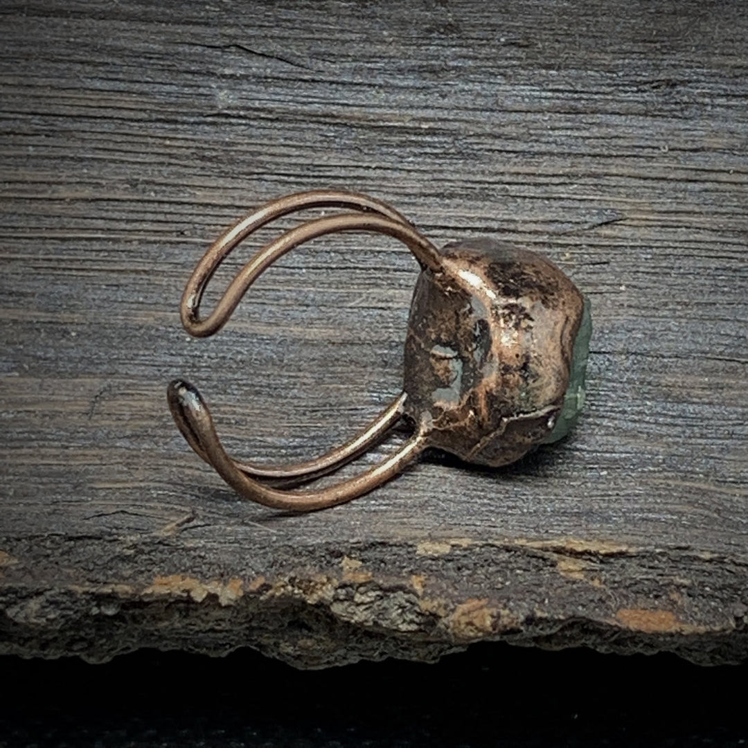 Antiker Kupferring mit grünem Stein auf rustikalem Holz, handgefertigter Schmuck, Vintage-Stil.