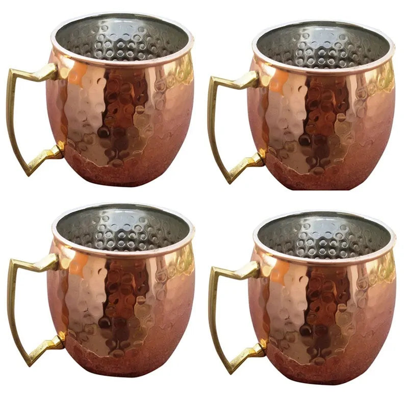 Vier Kupferbecher mit gehämmertem Design und goldenen Griffen für Moscow Mule Cocktails.
