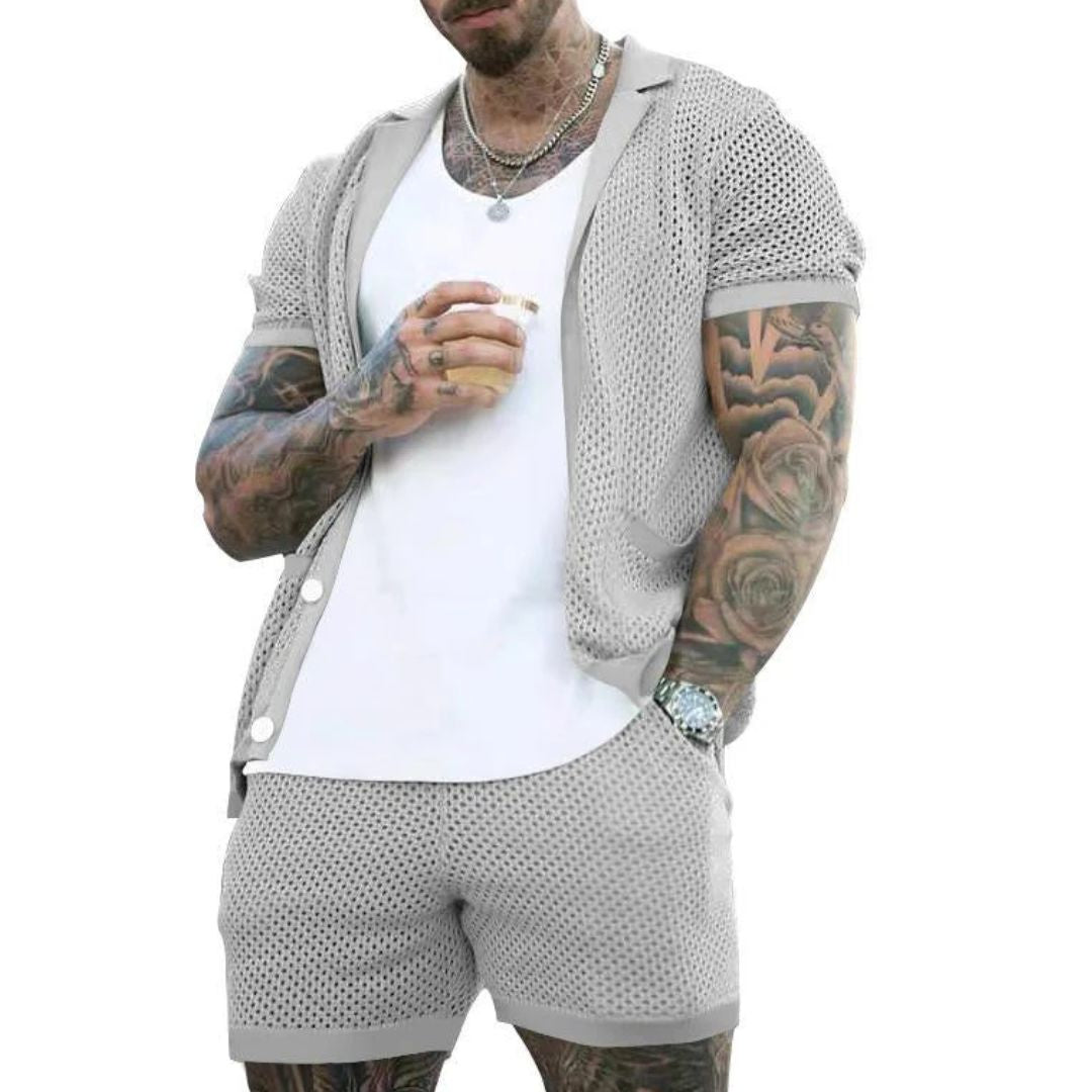 Mann in grauem Netz-Shorts-Set, weißes T-Shirt, tätowiert, hält Getränk, Sommermode.