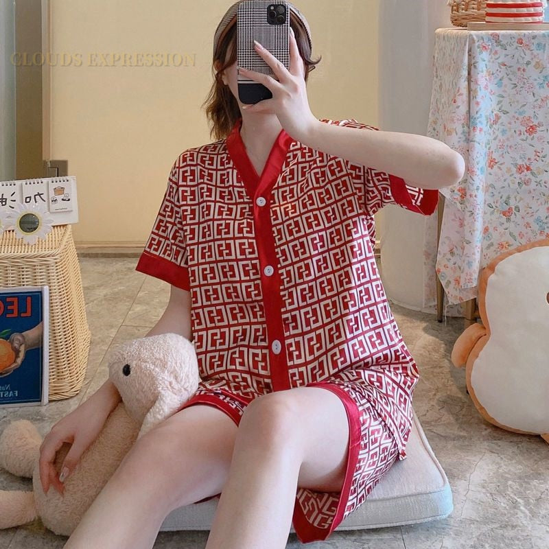 Frau in rotem Pyjama mit geometrischem Muster, sitzt auf Boden, Selfie mit Handy.