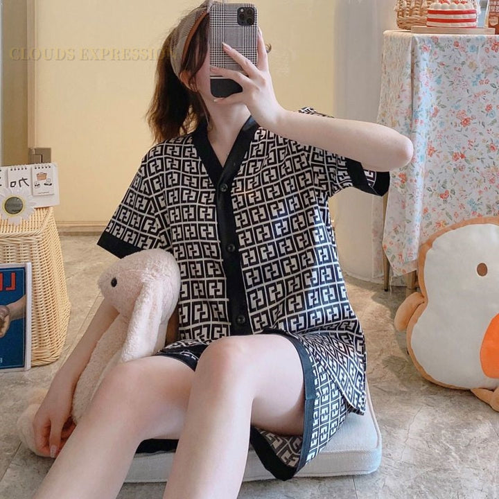 Frau in schwarz-weißem Pyjama mit geometrischem Muster, sitzt auf Kissen, Selfie machend.