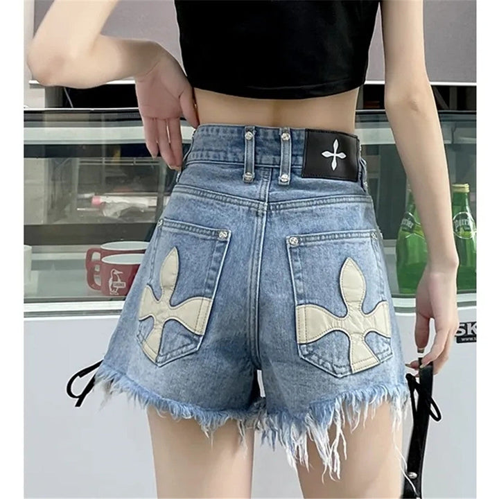 Frau in blauen Jeansshorts mit weißen Kreuzmotiven, schwarzes Top, modisch, Sommerkleidung.