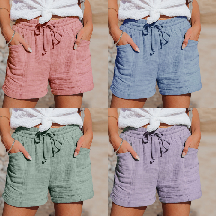 Vier Damen-Shorts aus Baumwolle in Rosa, Blau, Grün und Lila mit Kordelzug und Taschen.