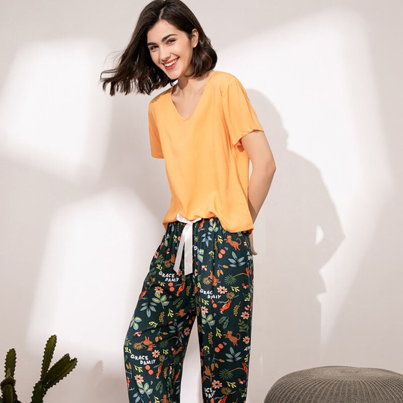 Frau in gelbem T-Shirt und floraler Hose, lächelnd, modisch, Freizeitkleidung, Innenraum.