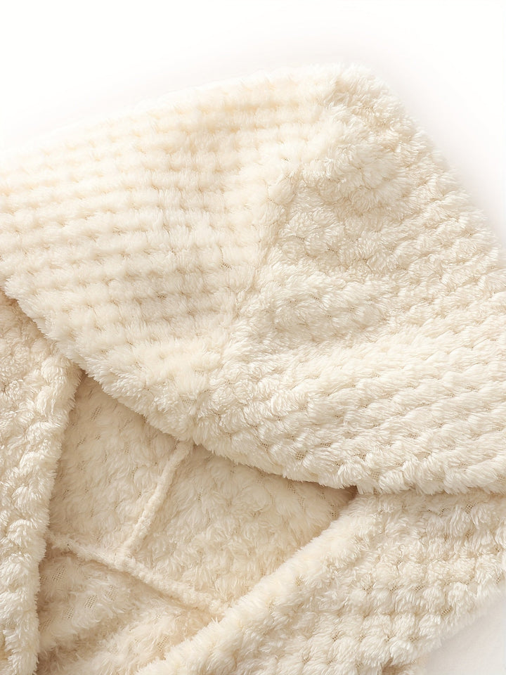 Beige Plüschdecke, weiches Material, waffelartige Textur, gemütlich, warm, Heimdekoration.