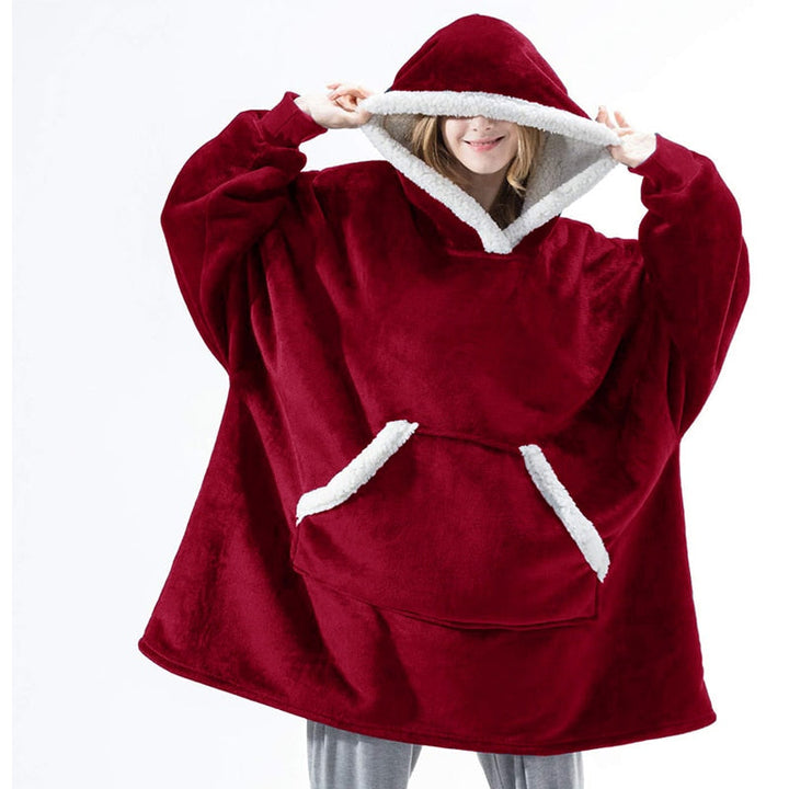 Frau in rotem, übergroßem Hoodie-Decke mit Kapuze und Tasche, gemütliche Winterbekleidung.