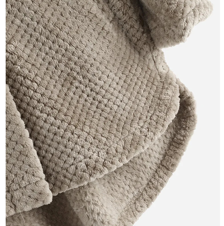 Beigefarbene, flauschige Decke aus Kunstfell, ideal für gemütliche Wohnräume.