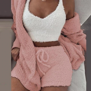 Frau in rosa Fleece-Shorts und weißem Top, gemütliches Lounge-Set, modisch, bequem.