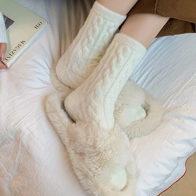 Weiße Wollsocken und flauschige Hausschuhe auf Bett, gemütliche Wintermode.