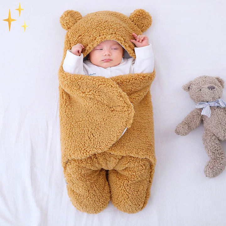Schlafender Säugling in braunem, flauschigem Babyschlafsack mit Bärenohren, neben Plüschtier.