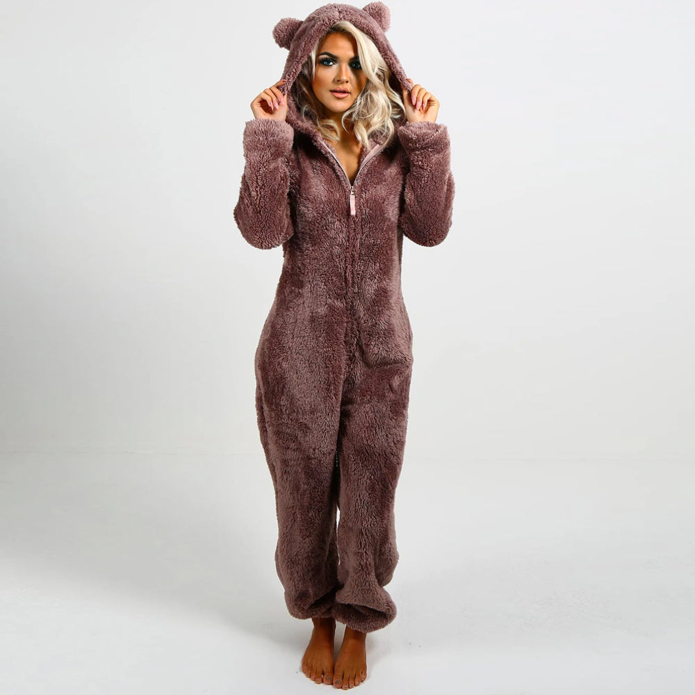 Frau in braunem Plüsch-Onesie mit Kapuze und Bärenohren, gemütlicher Einteiler für Damen.