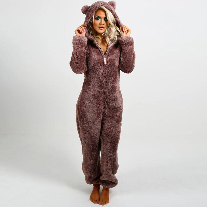 Frau in braunem Plüsch-Onesie mit Kapuze und Bärenohren, gemütlicher Einteiler für Damen.