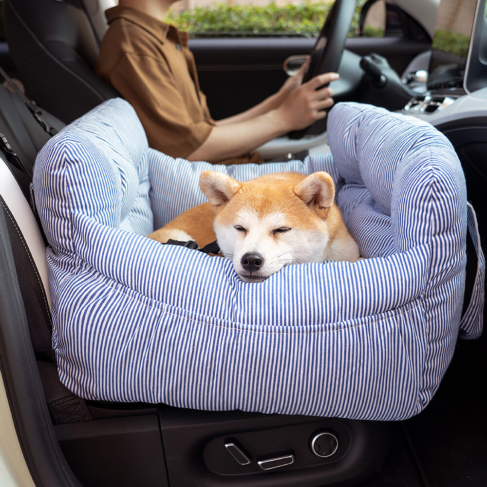 Hund schläft auf blau-weiß gestreiftem Haustierkissen im Auto, gemütlich, bequem, modisch.