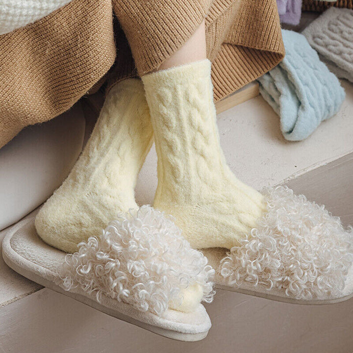 Gelbe Wollsocken und flauschige Hausschuhe auf Holzfußboden, gemütliche Wintermode.
