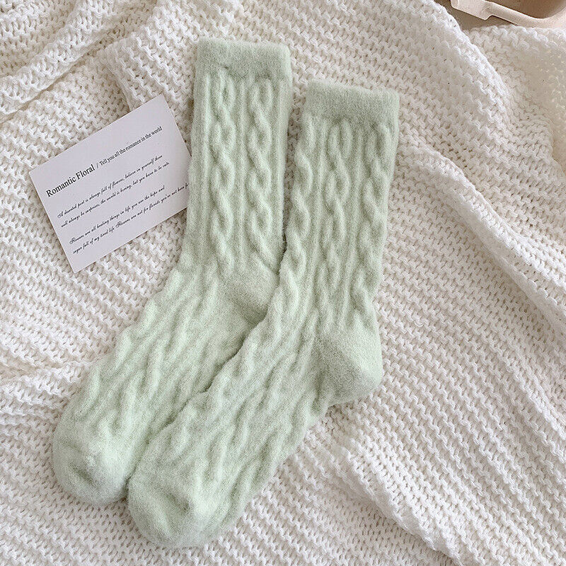 Weiche, grüne Stricksocken auf weißem Strickhintergrund, gemütliche Wintermode.