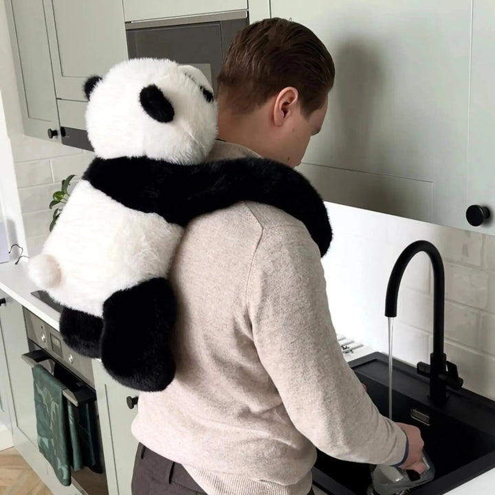 Muž u kuchyňského dřezu nosí pandu na zádech, její dlouhé paže mu obepínají ramena, zatímco myje nádobí. 10