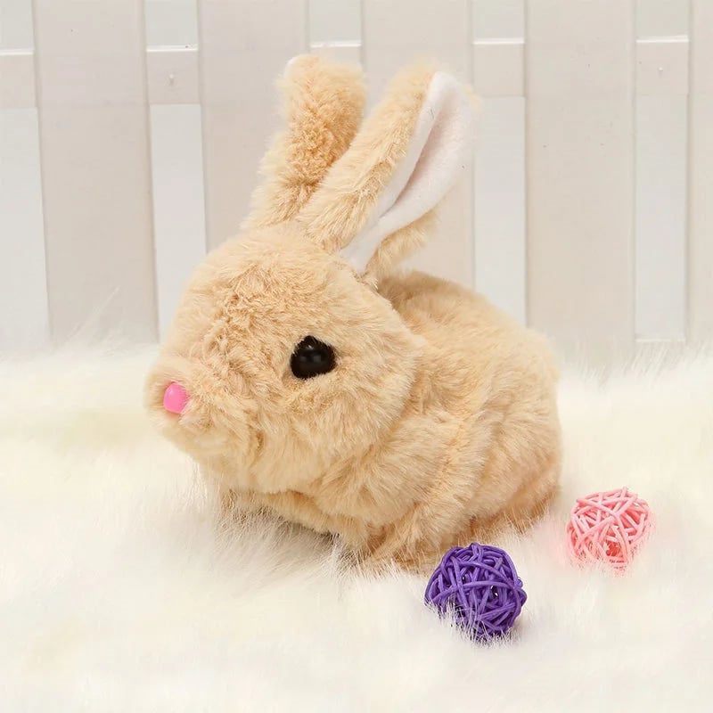 Kuscheltier Hase Plüsch beige, sitzend auf weißem Fell, mit lila und rosa Bällen, Spielzeug.