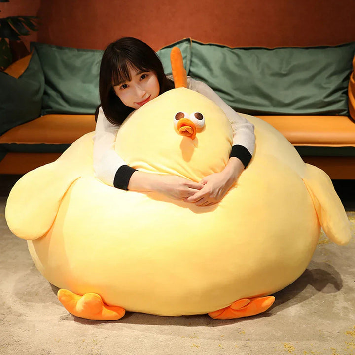 Frau umarmt großes gelbes Huhn Plüschtier, weiches Kuscheltier, Wohnzimmer, Geschenkidee.