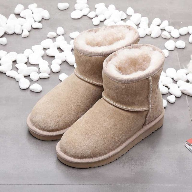 Beige Damen-Winterstiefel aus Wildleder mit Fellfutter auf grauem Boden, umgeben von weißen Steinen.