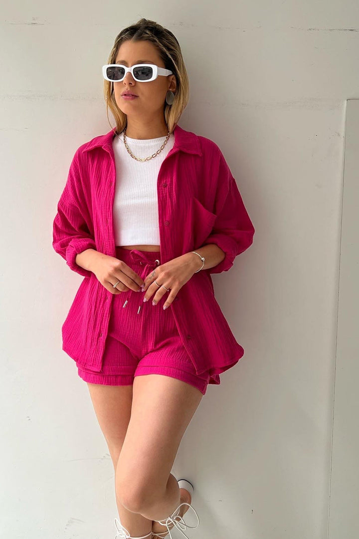 Frau in pinkem Langarmhemd und Shorts-Set, weißes Top, Sonnenbrille, modisch, lässig.