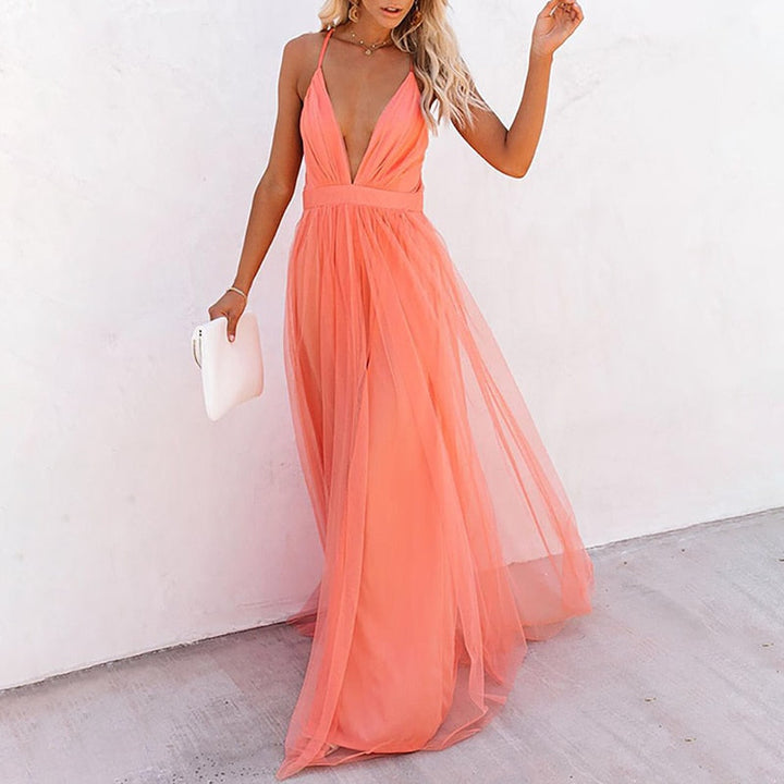 Frau im pfirsichfarbenen Abendkleid aus Tüll mit tiefem Ausschnitt, hält weiße Clutch.