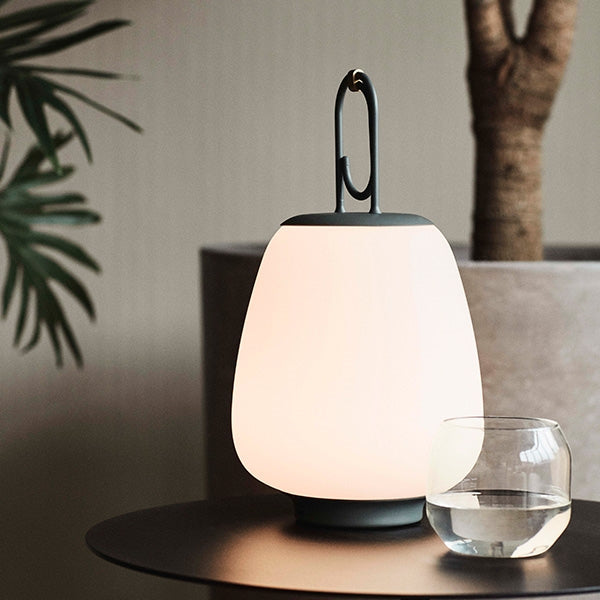 Moderne LED-Tischlampe, weiß, auf Tisch neben Glas, stilvolles Innendesign.