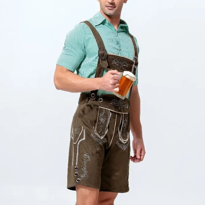Mann in brauner Lederhose mit Bierkrug, grünem Hemd, traditionelles bayerisches Outfit.