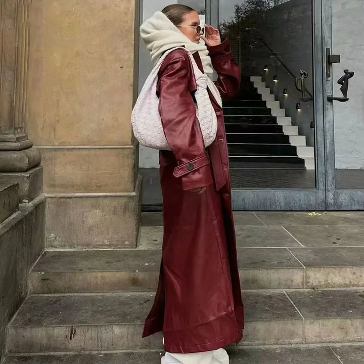 Frau in rotem Ledermantel mit weißer Handtasche und Sonnenbrille auf Treppe.