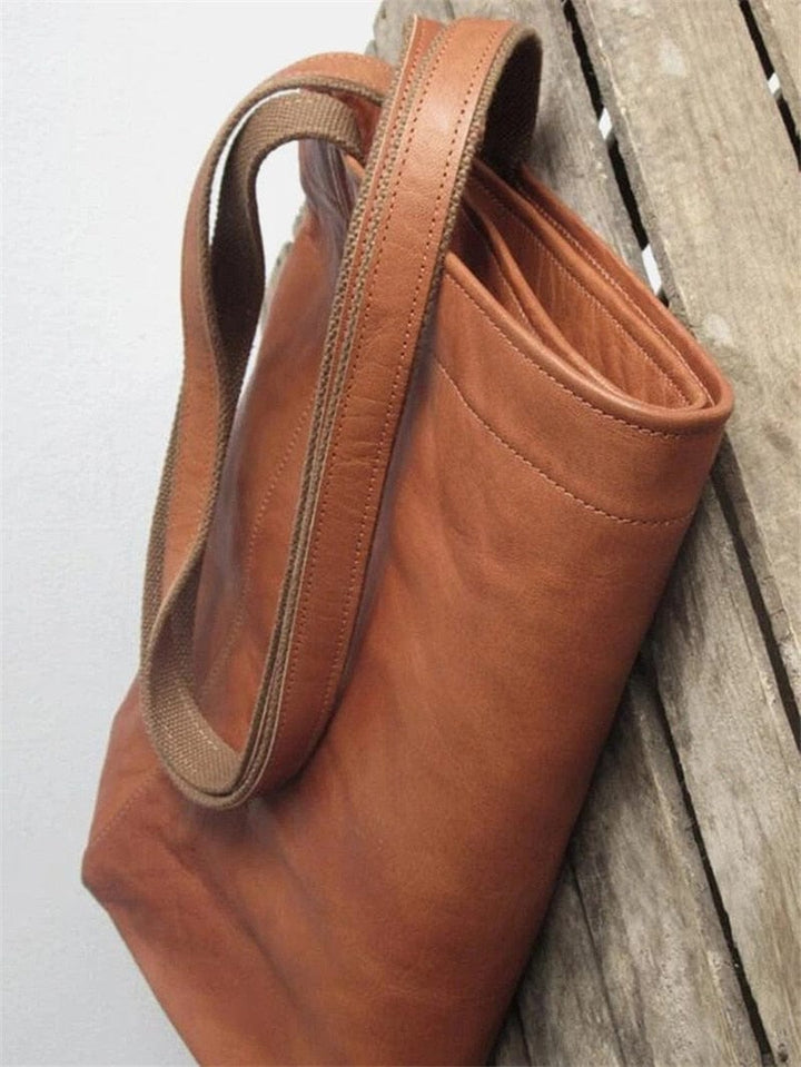 Braune Ledertasche mit robusten Trägern auf Holzhintergrund, langlebige Tragetasche.