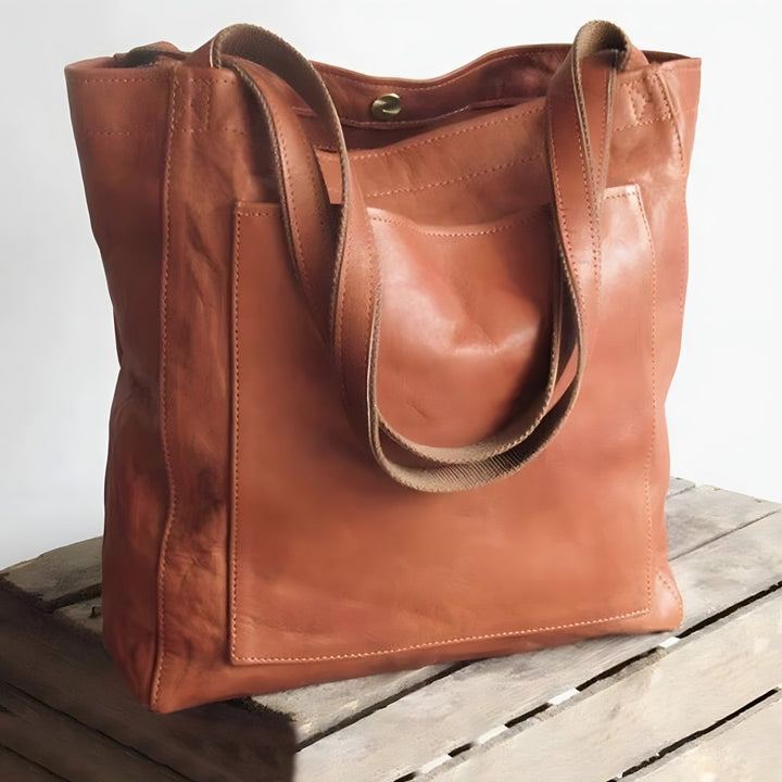 Braune Ledertasche mit Tragegriffen auf Holzkiste, modisch, geräumig, hochwertig.