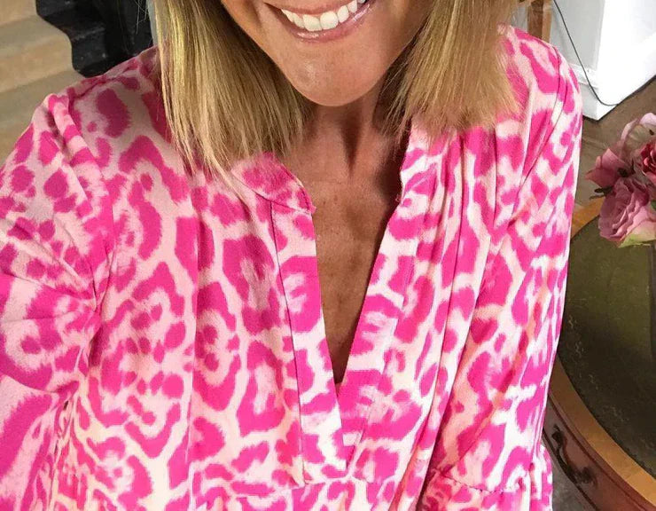 Frau in pinkem Leopardenmuster-Kleid, lächelnd, modisch, Sommerkleidung, Nahaufnahme.