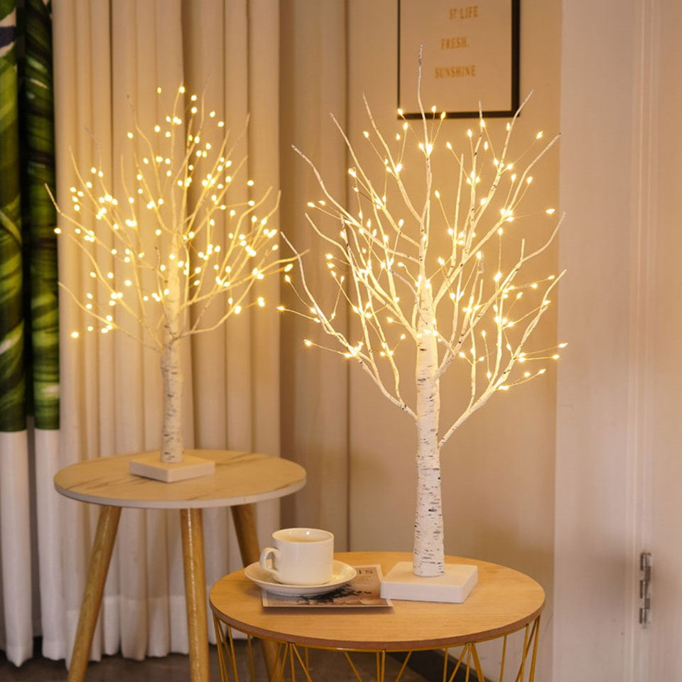 Zwei LED-Baumlichter auf Holztischen, warmweiß leuchtend, dekorative Beleuchtung, Innenraum.