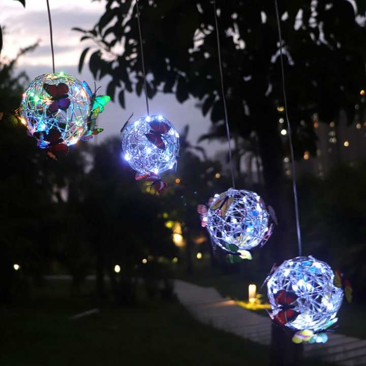 Hängende LED-Solarlichter mit Schmetterlingen im Garten bei Nacht.