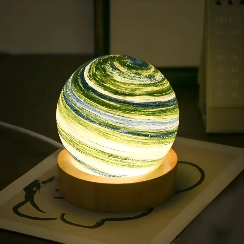 Leuchtende Tischlampe in Planetenform, grün-gelb, auf Holzsockel, dekorative Beleuchtung.