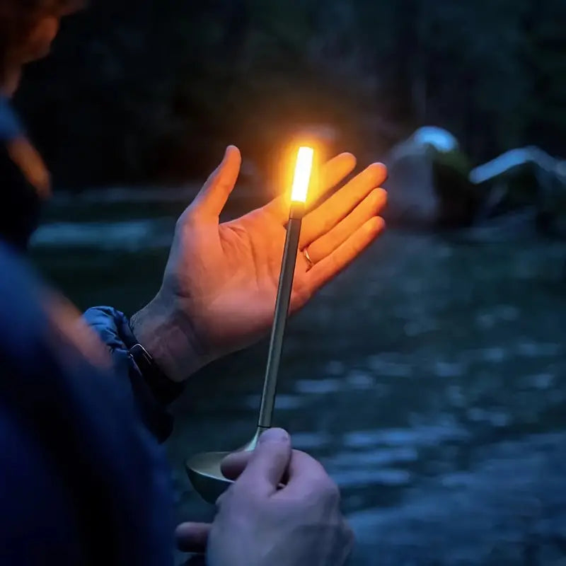 Person hält leuchtende LED-Kerze im Freien, Nacht, Hand, Beleuchtung, Camping, tragbar.