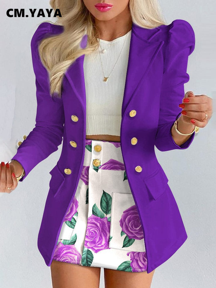 Frau in lila Blazer mit goldenen Knöpfen, weißem Top und floralem Rock, modisch elegant.