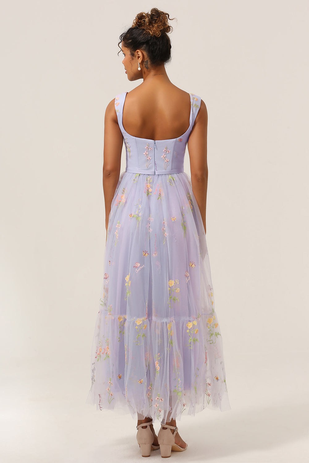 Frau in langem, lila Abendkleid mit Blumenmuster, ärmellos, elegantes Design.