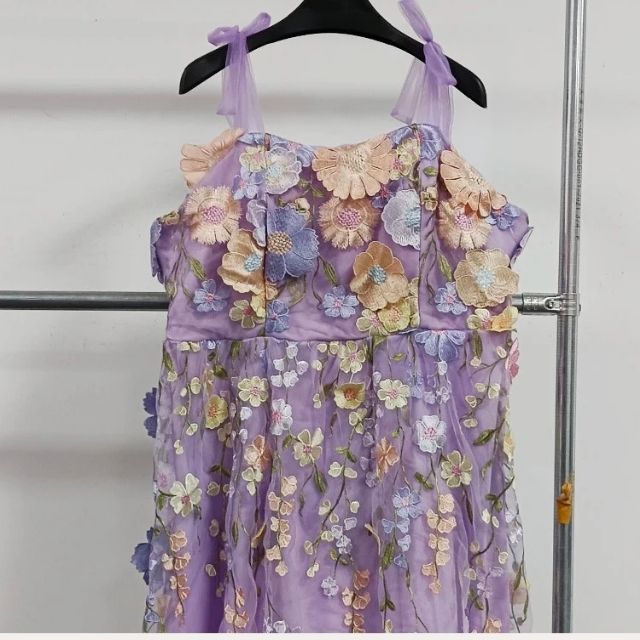 Lila Kleid mit Blumenstickerei, ärmellos, aus Tüll, auf Kleiderbügel, festlich, elegant.
