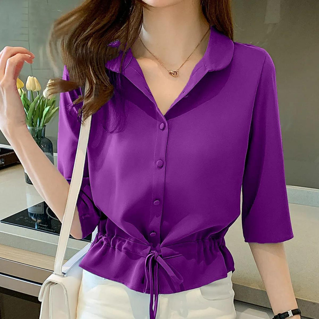Frau in lila Bluse mit Kordelzug, weiße Hose, moderne Küche, modische Damenbekleidung.