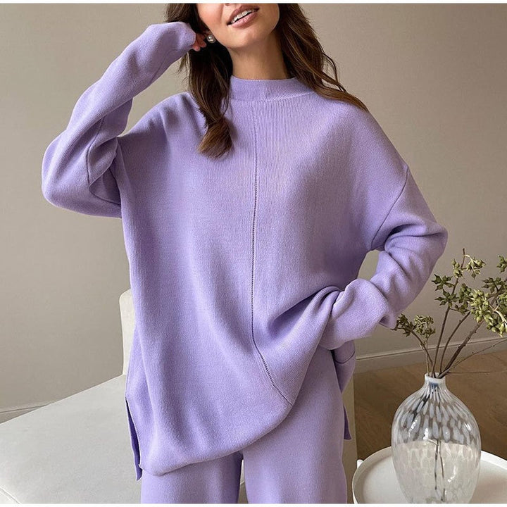 Frau in lila Oversize-Pullover und Hose, gemütliche Damenmode, Wohnzimmer, moderne Einrichtung.