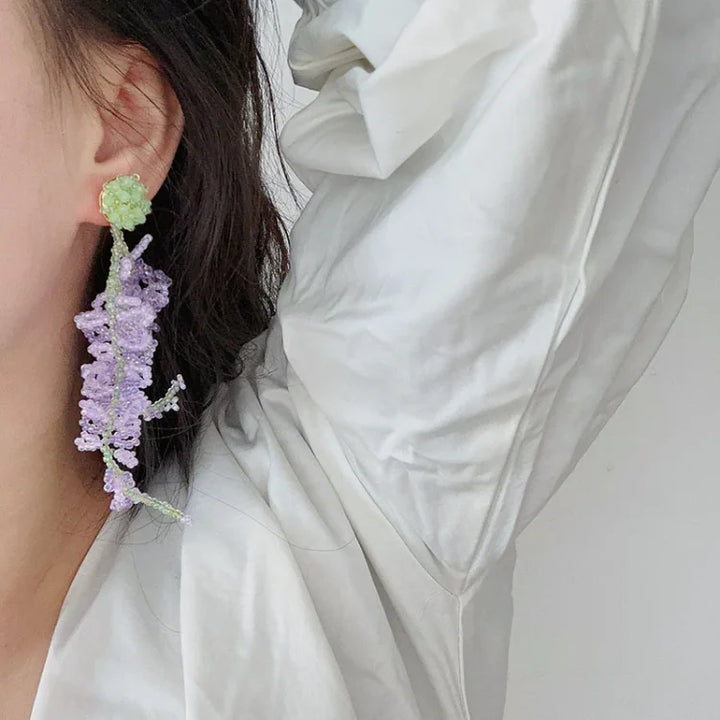 Frau mit handgefertigtem Ohrring aus lila und grünem Perlen, elegantes Schmuckdesign.