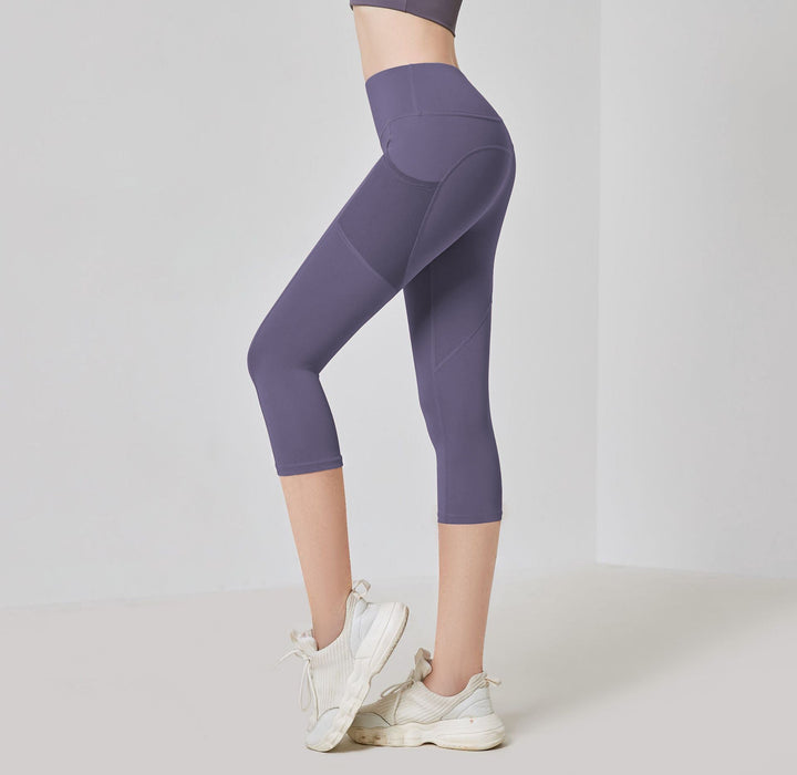 Frau in lila Sportleggings, knielang, mit weißen Turnschuhen, Fitnessmode, seitliche Ansicht.