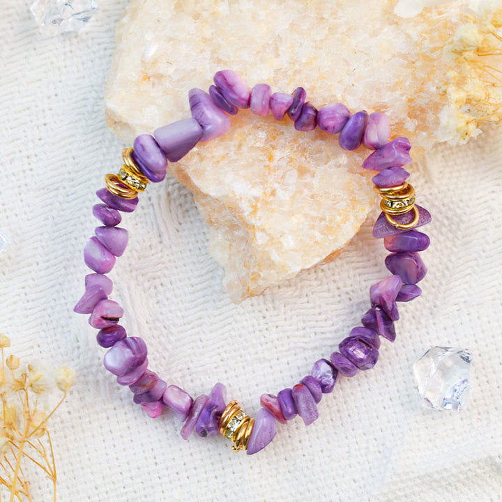 Lila Edelstein-Armband mit goldenen Akzenten auf hellem Hintergrund, Schmuck, Modeaccessoire.