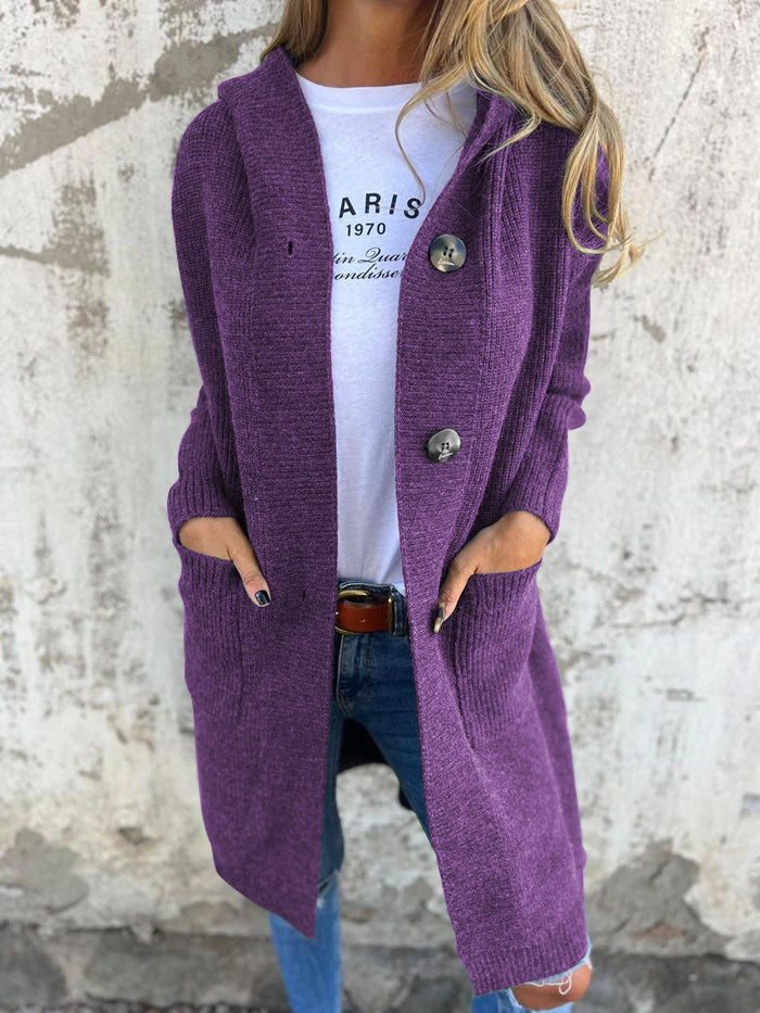 Frau in lila Strickjacke mit Knöpfen, weiße T-Shirt, blaue Jeans, lässiger Herbstlook.