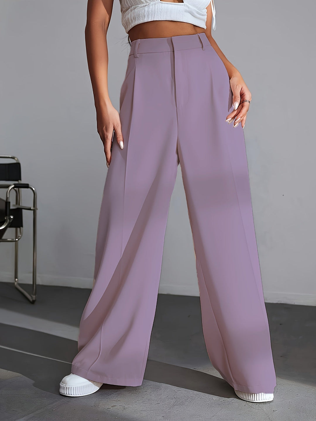 Frau in lila, weiten Hosen und weißem Top, modisch, elegant, moderne Damenmode.