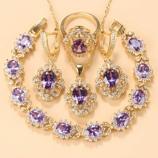 Goldene Schmuckset mit lila Zirkonia, bestehend aus Armband, Ring, Ohrringen und Anhänger.