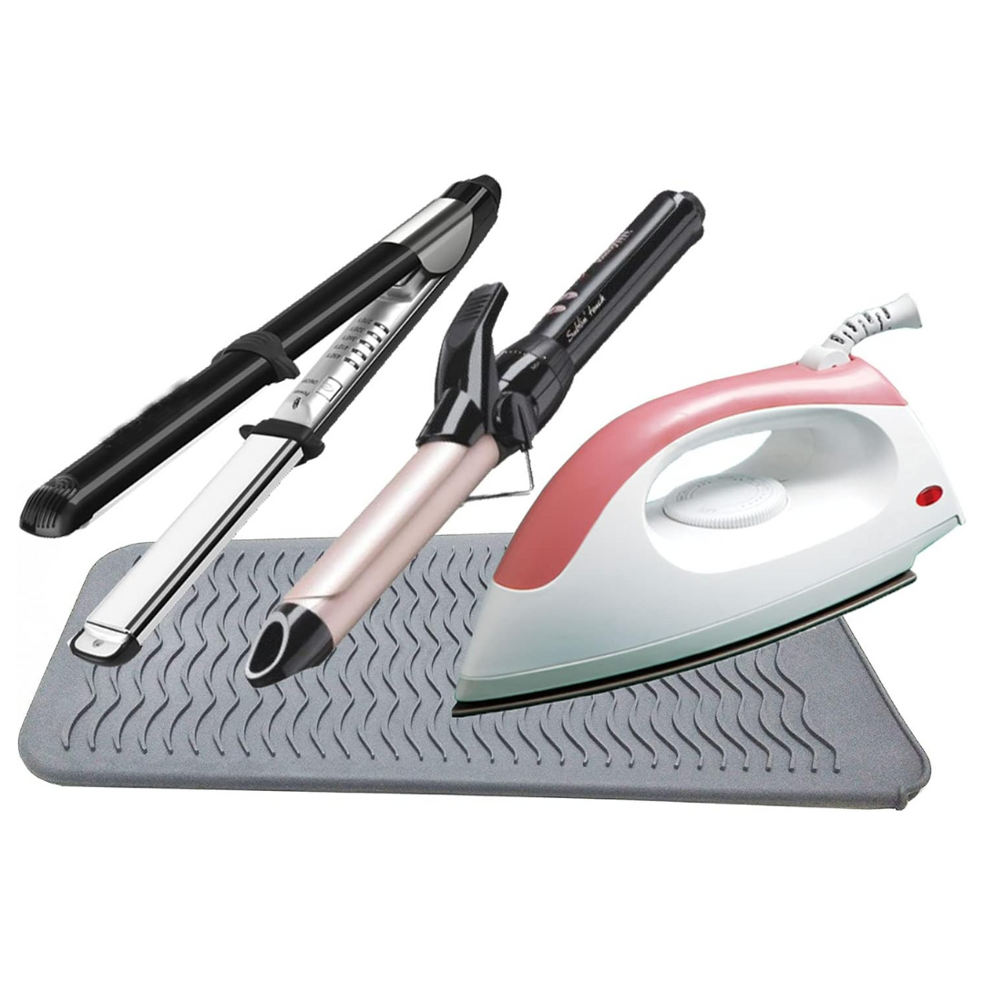 Lockenstäbe und Bügeleisen auf grauer Silikonmatte, Haarstyling und Bügelzubehör.