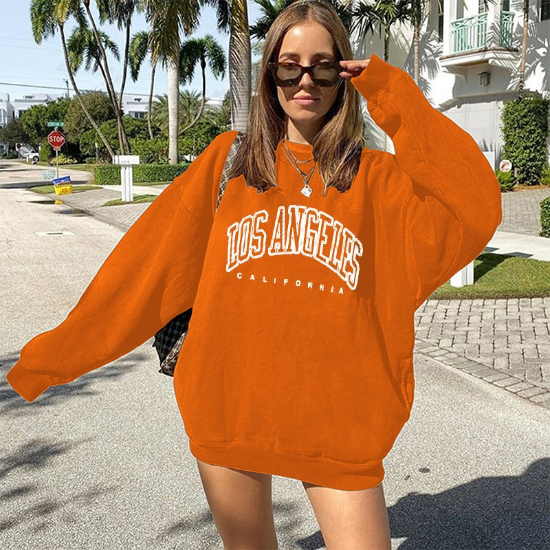 Frau in orangefarbenem Los Angeles Sweatshirt, lässige Mode, Sommer, Straße, Palmen.