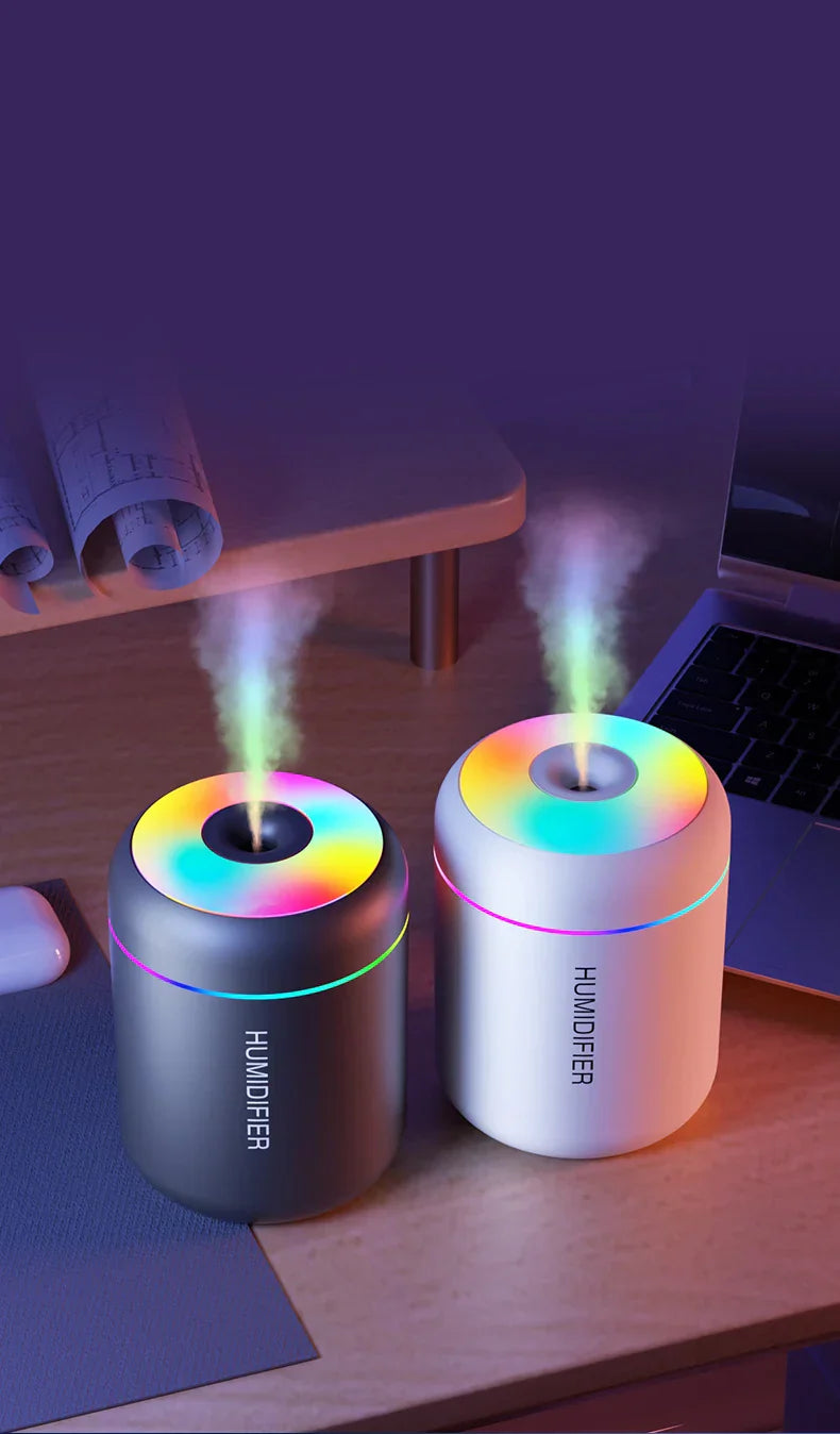 Zwei LED-Luftbefeuchter, schwarz und weiß, auf Schreibtisch, mit farbigem Licht und Dampf.