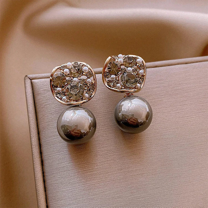 Elegante Ohrringe mit Perlen und Kristallen, goldfarben, luxuriöses Schmuckdesign.